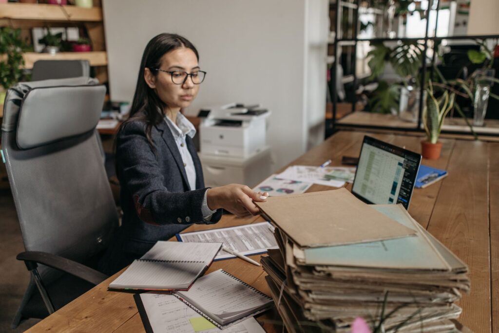 Automatización de tareas administrativas para PYMES 1 automatización de tareas administrativas: Administrativa de una pequeña empresa revisando documentos y tareas repetitivas junto a un portátil