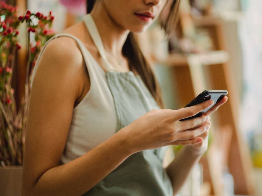 Propietaria de un comercio revisando en su móvil la visibilidad de su SEO local para pymes